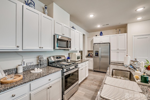 224 Park Ln, Dunellen, NJ 08812 - kitchen with appliances with stainless steel finishes, white cabinetry, dark stone counters, light wood-style floors, and recessed lighting