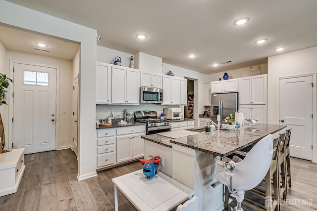 224 Park Ln, Dunellen, NJ 08812 - kitchen with stainless steel appliances, a kitchen bar, light wood-style floors, white cabinets, and recessed lighting