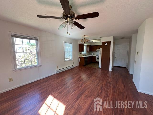 unfurnished living room featuring dark wood-style flooring, baseboard heating, ceiling fan, a textured ceiling, and baseboards