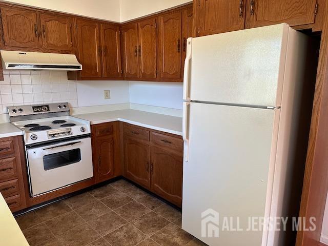 kitchen featuring light countertops, white appliances, ventilation hood, and tasteful backsplash