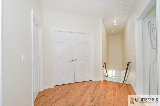 hallway with attic access, an upstairs landing, light wood-style flooring, baseboards, and recessed lighting