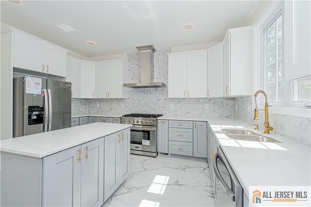 kitchen with stainless steel appliances, wall chimney range hood, a sink, light marble finish floors, and gray cabinets