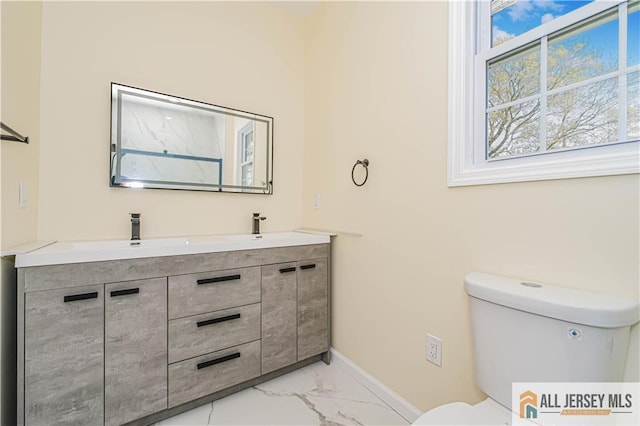 bathroom featuring marble finish flooring, toilet, baseboards, and double vanity