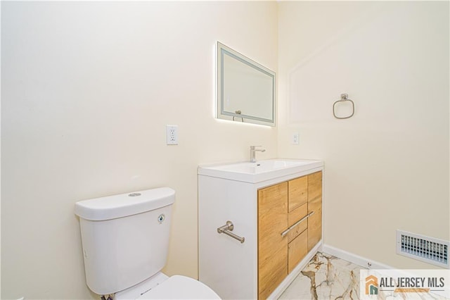 half bathroom with marble finish floors, toilet, and vanity