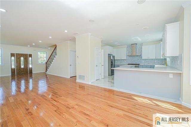 unfurnished living room with baseboards, light wood-style floors, recessed lighting, stairway, and crown molding
