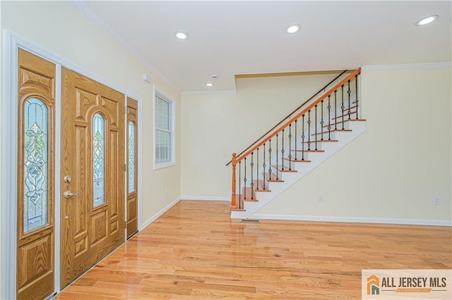 foyer with ornamental molding, baseboards, recessed lighting, stairway, and light wood-style floors