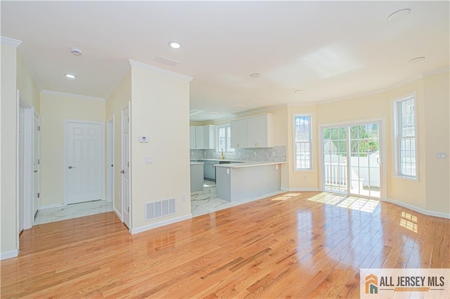 unfurnished living room with light wood finished floors, crown molding, baseboards, and recessed lighting