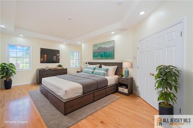 bedroom featuring a tray ceiling, light wood-style floors, recessed lighting, and baseboards