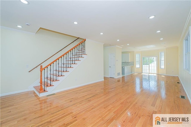 unfurnished living room featuring ornamental molding, recessed lighting, baseboards, stairway, and light wood-type flooring