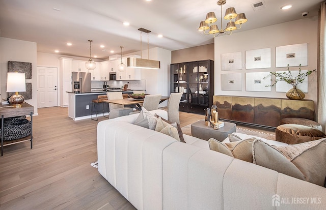 living room featuring sink, a chandelier, and light wood-type flooring