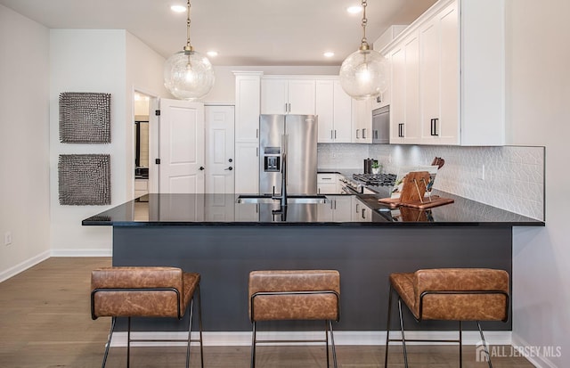 kitchen featuring white cabinetry, a kitchen bar, decorative light fixtures, and high end fridge