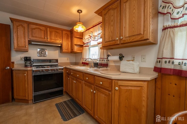 kitchen featuring brown cabinets, light countertops, range with gas stovetop, and under cabinet range hood