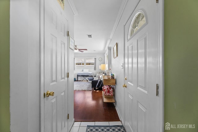 corridor with light tile patterned floors, crown molding, and baseboards