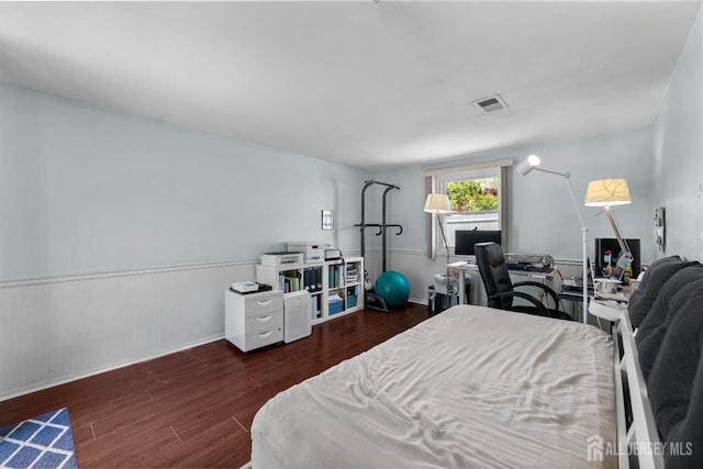 bedroom with wood finished floors, wainscoting, an office area, and baseboards