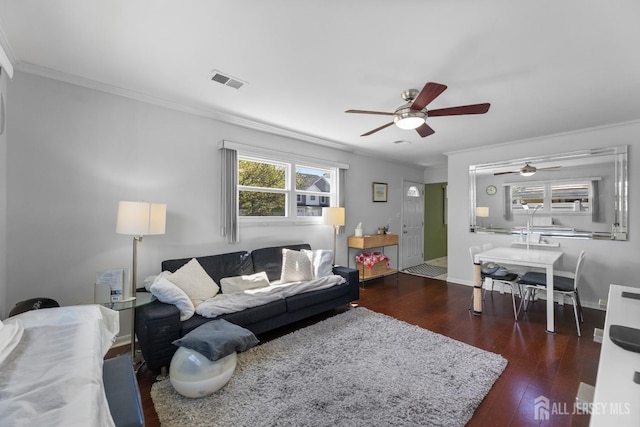living area featuring a ceiling fan, crown molding, wood finished floors, and baseboards