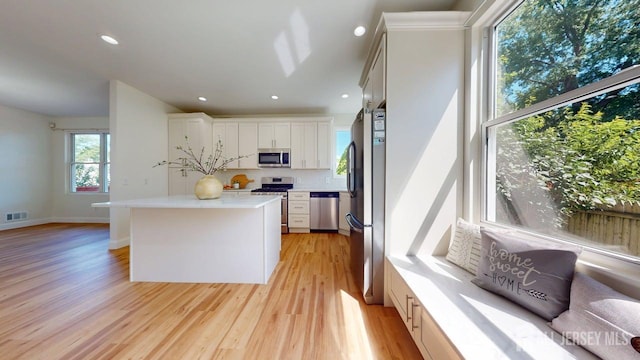 15-A Avenue B, Helmetta, NJ 08828 - kitchen with appliances with stainless steel finishes, light wood finished floors, tasteful backsplash, light countertops, and a center island