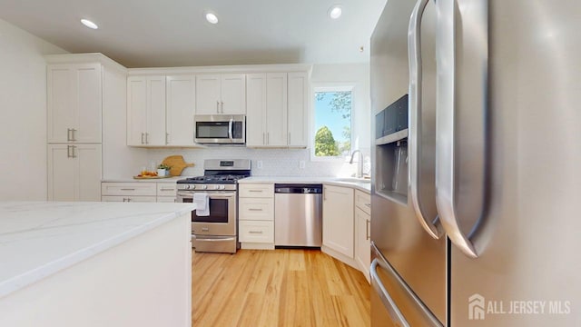 15-A Avenue B, Helmetta, NJ 08828 - kitchen with stainless steel appliances, backsplash, white cabinetry, light wood-style floors, and light stone counters