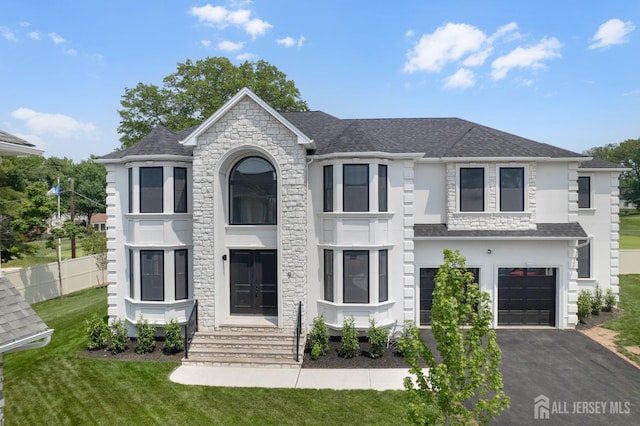 9 Links Dr, Edison, NJ 08820 - french country style house with asphalt driveway, an attached garage, a front yard, roof with shingles, and stucco siding