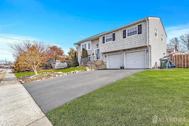 raised ranch with driveway, an attached garage, and a front lawn