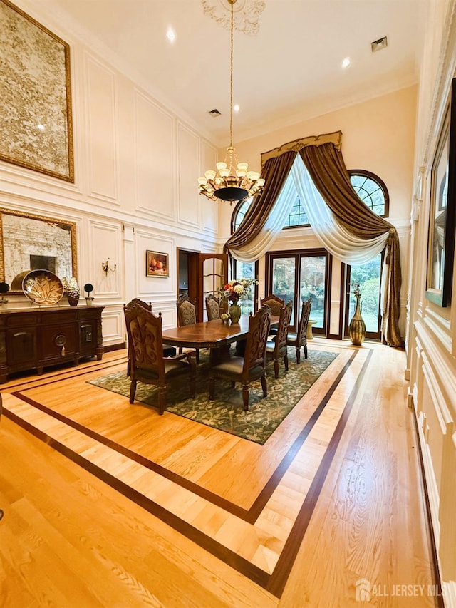 34 Line Rd, Holmdel, NJ 07733 - dining area with a high ceiling, a chandelier, a decorative wall, light wood-type flooring, and crown molding