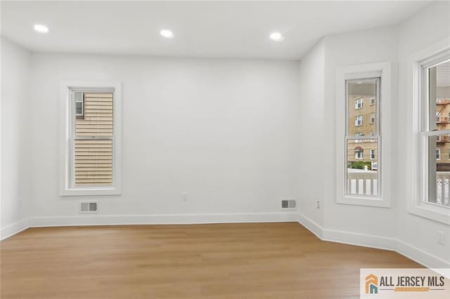 spare room with light wood finished floors, baseboards, visible vents, and recessed lighting