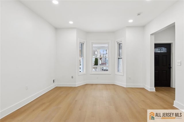 spare room with baseboards, light wood finished floors, and recessed lighting