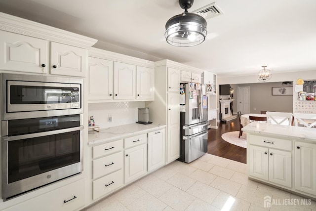 242 Green St, Old Bridge, NJ 08857 - kitchen featuring stainless steel appliances, light stone countertops, white cabinetry, light tile patterned floors, and a chandelier