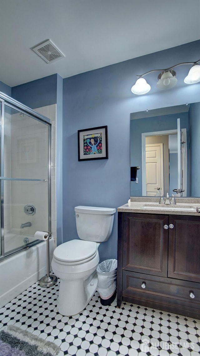 bathroom with toilet, bath / shower combo with glass door, vanity, and visible vents