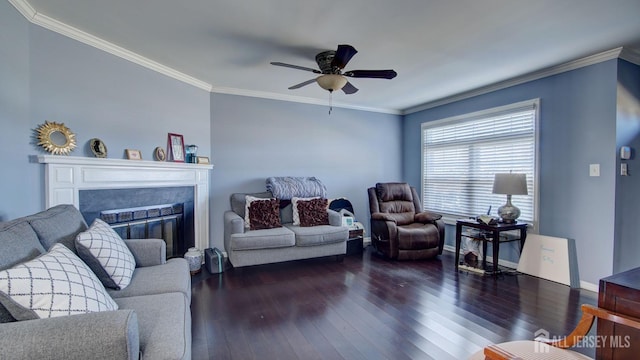 living room with ceiling fan, dark wood finished floors, crown molding, and a glass covered fireplace