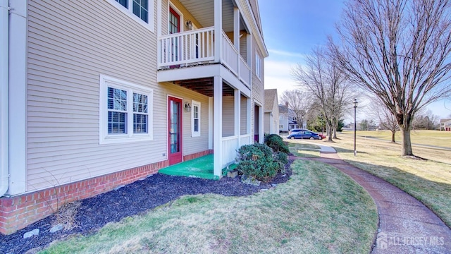 view of side of home with a balcony and a yard