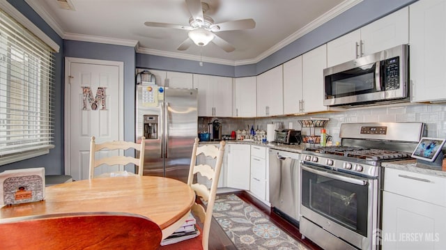 kitchen with stainless steel appliances, white cabinetry, ornamental molding, backsplash, and light stone countertops