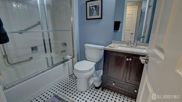 bathroom featuring toilet, shower / bath combination with glass door, and vanity