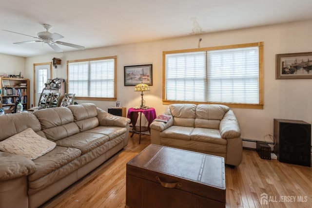 living room with light wood-style flooring, baseboard heating, and ceiling fan