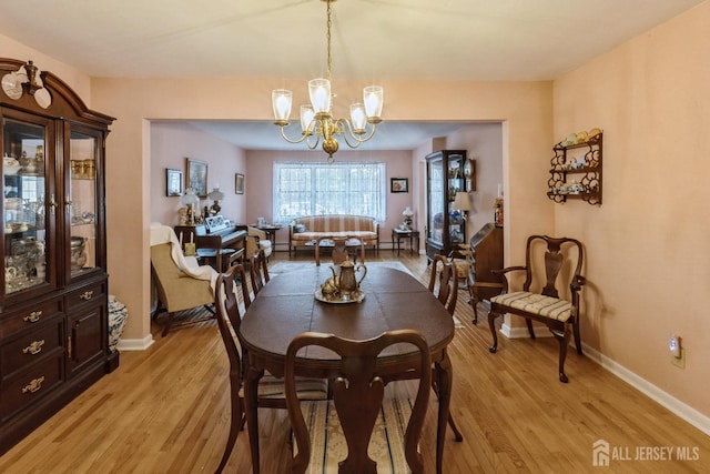 dining space with a chandelier, light wood-style flooring, and baseboards