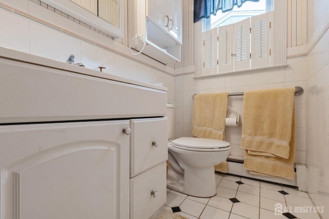 bathroom featuring tile patterned flooring, tile walls, toilet, and a baseboard radiator