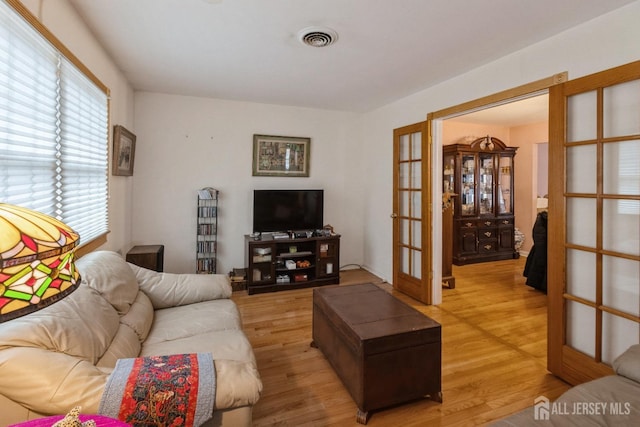 living area featuring light wood-type flooring, french doors, and visible vents