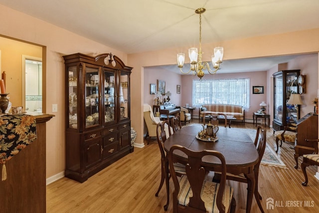 dining area featuring light wood-type flooring, baseboards, and an inviting chandelier