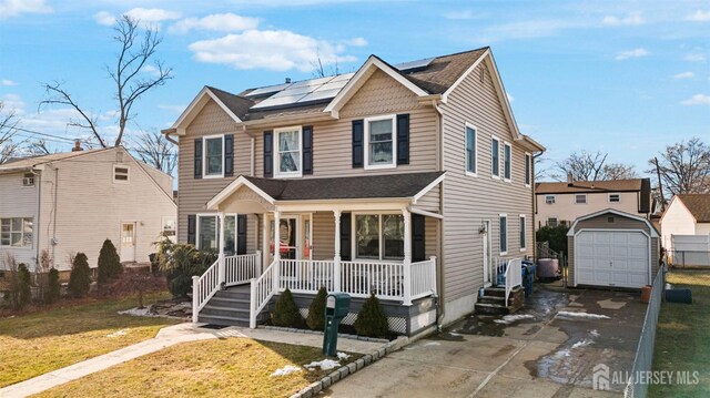 view of front of property featuring a porch, an outbuilding, a garage, a front yard, and solar panels