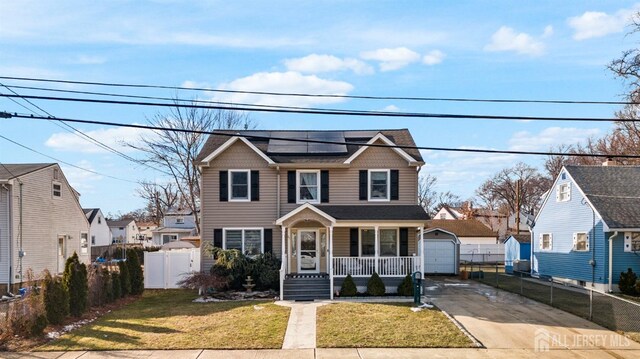 front of property featuring a porch, a garage, solar panels, an outbuilding, and a front lawn