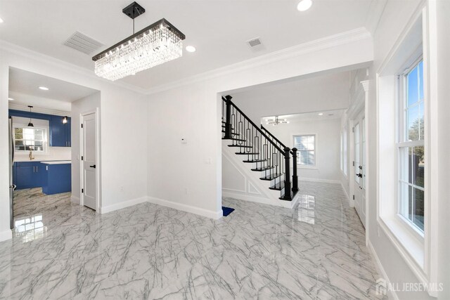 entryway with crown molding and an inviting chandelier