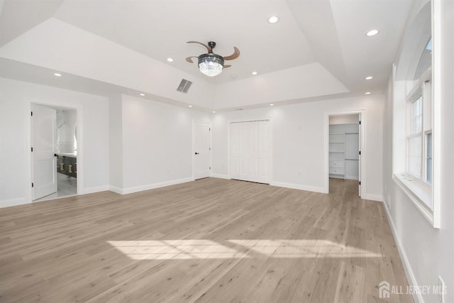 unfurnished living room with a tray ceiling, recessed lighting, visible vents, and light wood-style floors