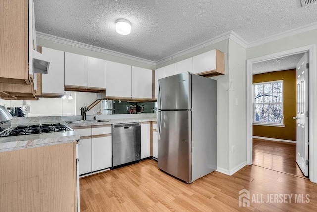 kitchen with sink, white cabinetry, crown molding, light wood-type flooring, and appliances with stainless steel finishes