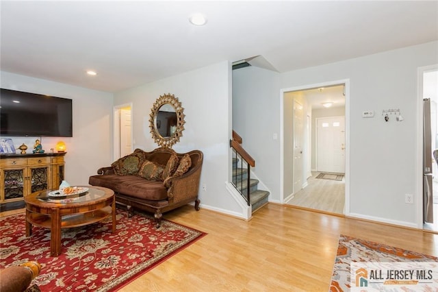 living area with recessed lighting, baseboards, wood finished floors, and stairs