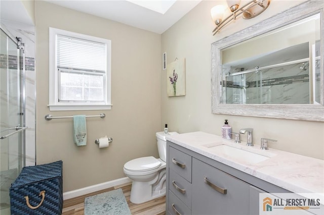 full bathroom featuring toilet, wood finished floors, a skylight, a shower stall, and baseboards