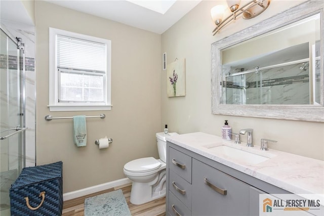 full bathroom with wood finished floors, a shower stall, toilet, vanity, and baseboards