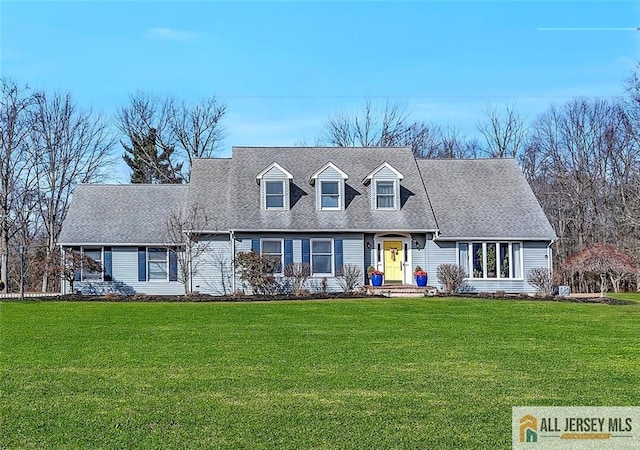 cape cod home with roof with shingles and a front yard