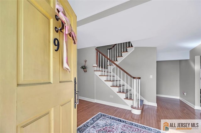 entrance foyer featuring stairway, baseboards, and dark wood-style flooring