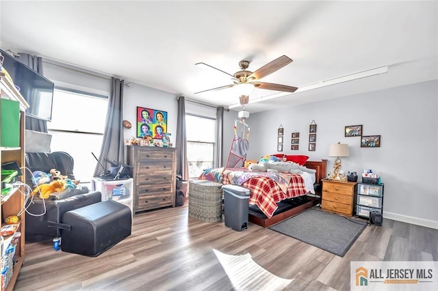 bedroom featuring ceiling fan, baseboards, and wood finished floors