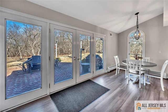 dining room with lofted ceiling, visible vents, baseboard heating, wood finished floors, and a chandelier