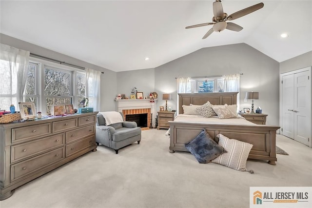 bedroom featuring lofted ceiling, multiple windows, a brick fireplace, and light colored carpet